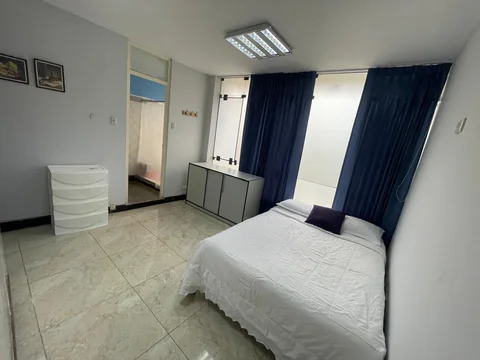 Dormitorio con cama, cómoda, espejo y cortinas azules